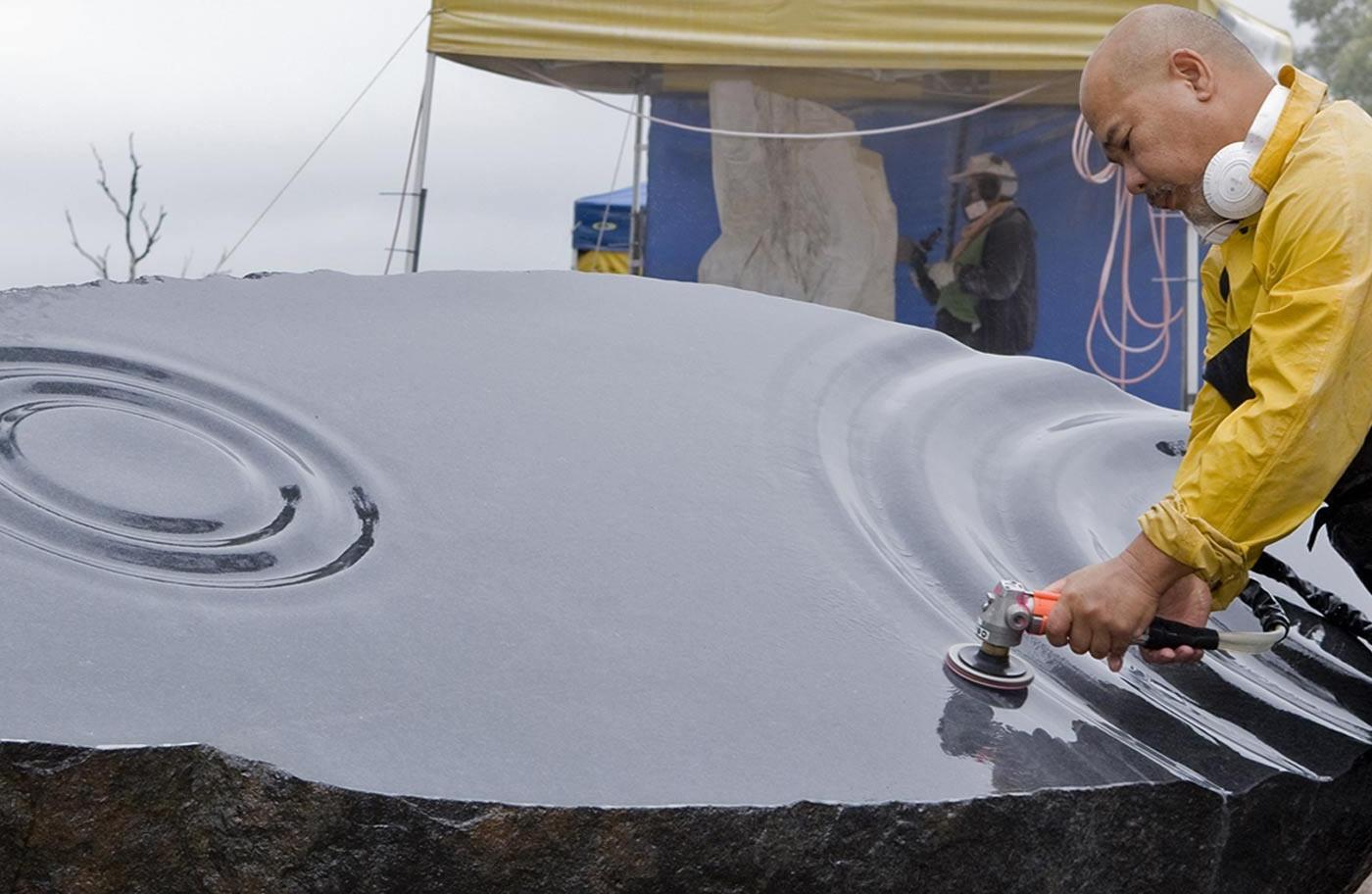 Man sculpting a stone to look like ripples on a lake